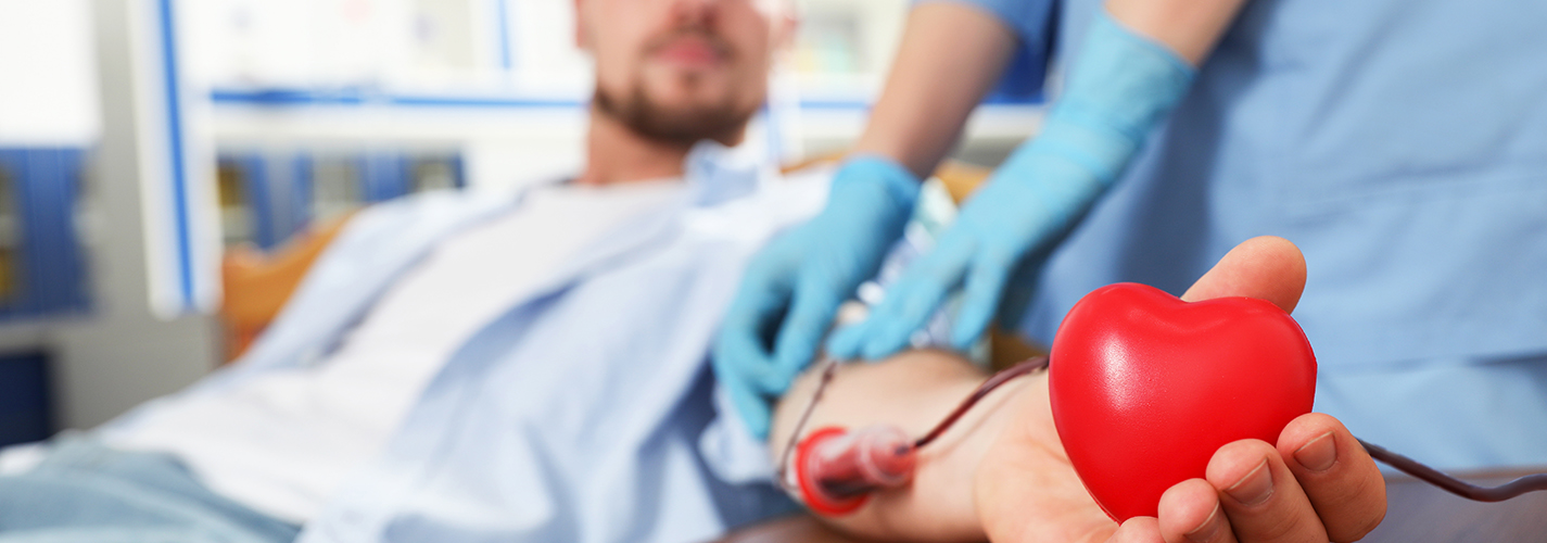 A person squeezes a red heart shaped stress ball while donating blood.