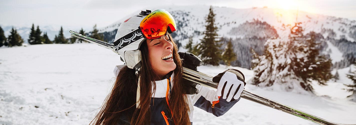 A woman smiles while skiing on a mountain top.