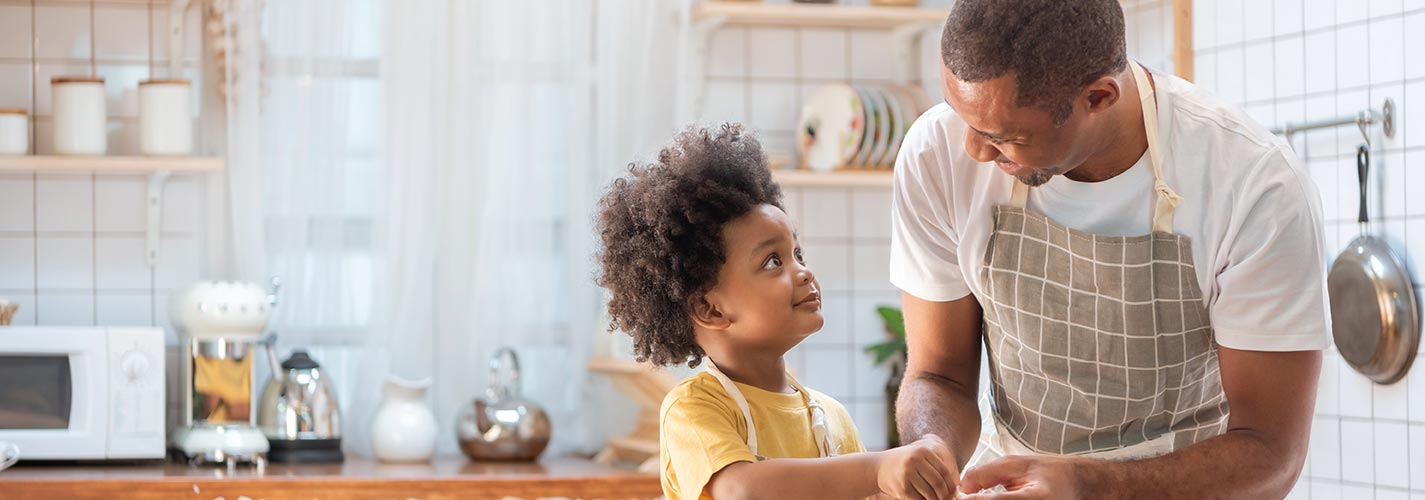 A man and his son are in the kitchen cooking dinner.