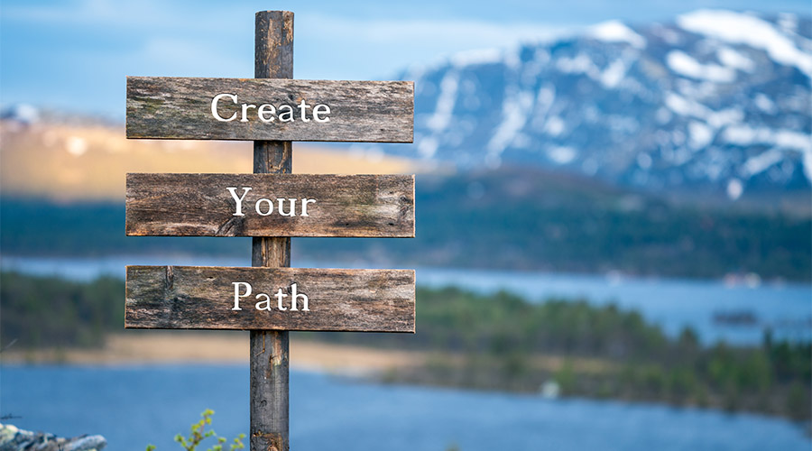 Developing a Success Mindset. A signpost by a beautiful lake that reads "Create Your Path".