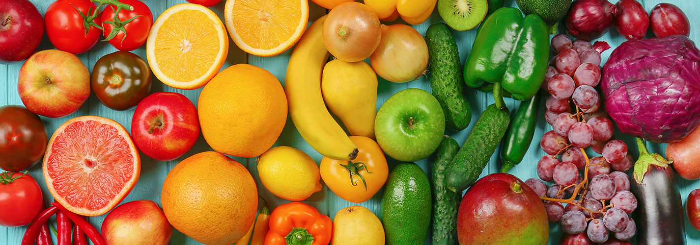 Composition made of fruits and vegetables in rainbow colors on wooden light blue background.