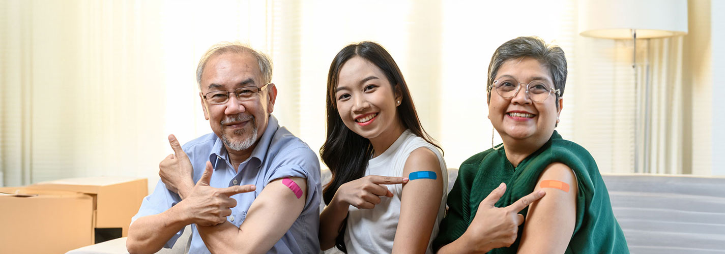 Three Asian family members of diverse ages showing their bandages on their arms after receiving the influenza vaccination to prevent contracting the Flu.