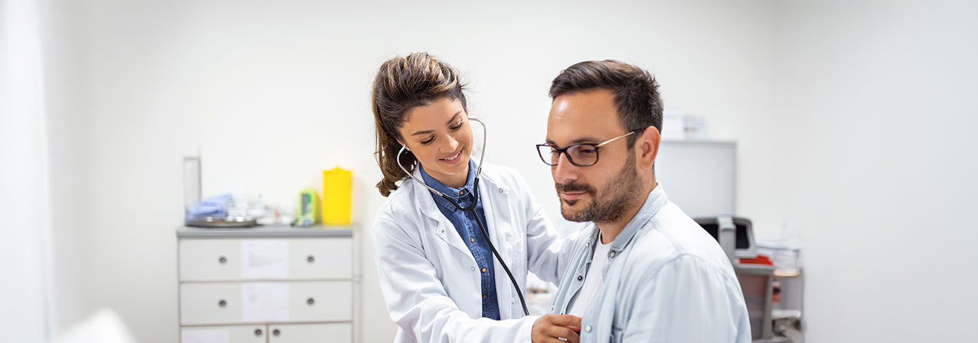 A doctor checks the heart of her male patient.