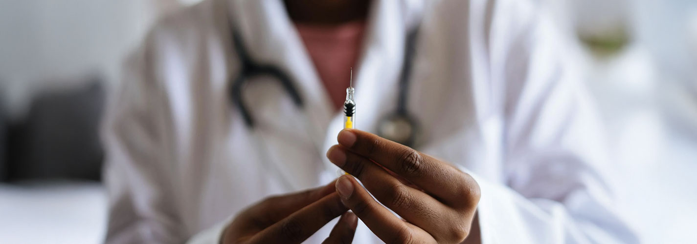 A close up of a doctor holding a syringe for a vaccine