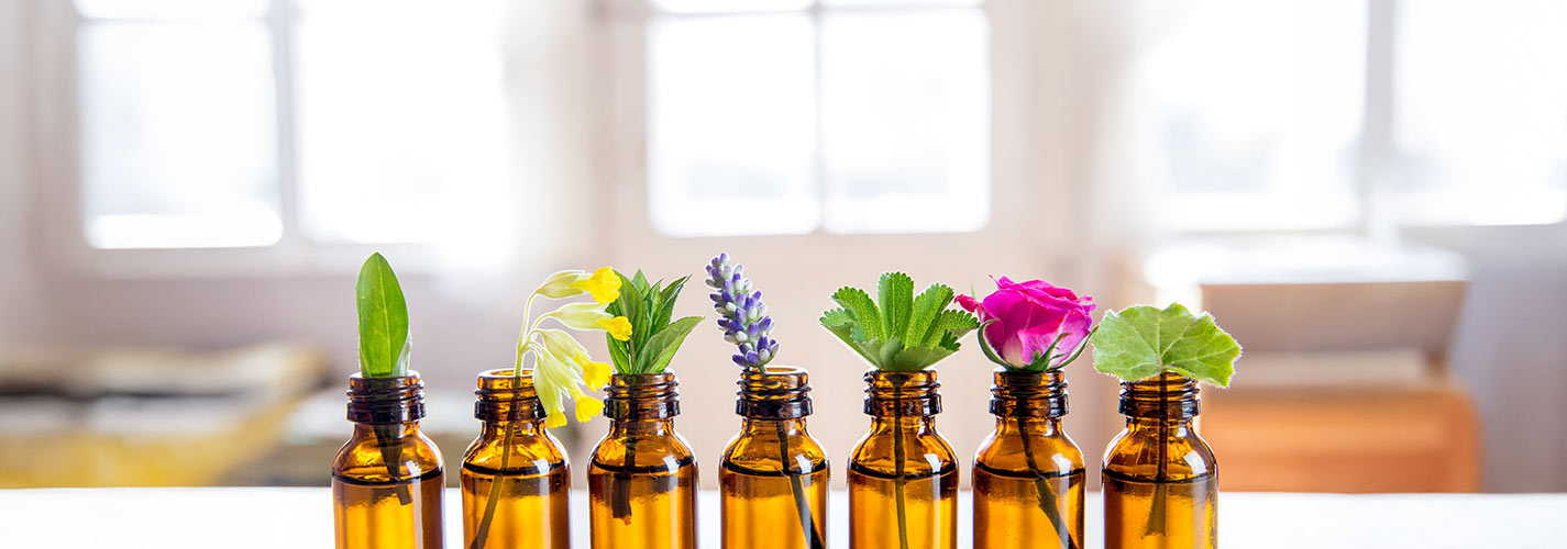 Amber glass bottles with various flowers and leaves in each bottle.